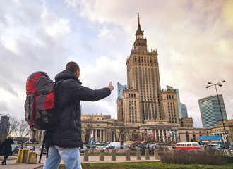 Young male tourist walking around the city and watching on Palace of Culture and Science in Warsaw. Having a happy vacation in Poland