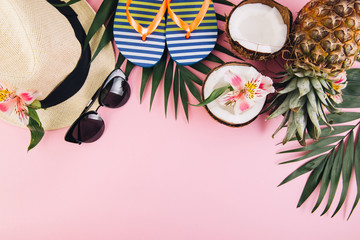 Tropical palm leaves, hat, slippers, sunglasses, pineapple, coconut on pink background. Summer concept. Flat lay, top view, copy space