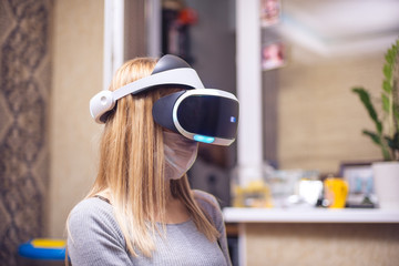A young blond caucasian sick girl covers her face and wears a Virtual Reality Headset enjoys...
