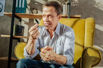 Unpleasant old man with brown eyes taking pills