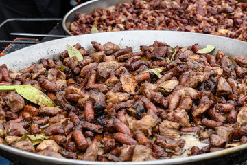 Two large pans with different types of deep fried meat pieces, in display for sale at a food market