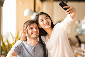 Young cheerful friends using smart phone together at the coffee shop