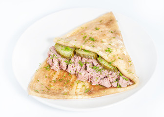 Thin delicious pancake with meat pate and cucumber on white