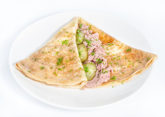 Thin delicious pancake with meat pate and cucumber on white
