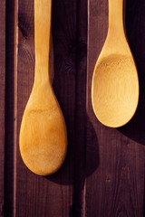 Wooden spoons one shorter than the other hang on a wooden Burgundy wall close-up.