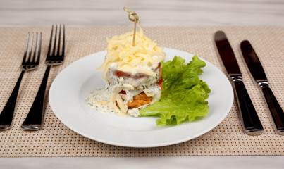 Sandwich with grilled meat tomato and cheese on a green leaf of lettuce.