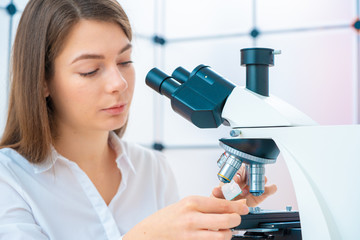 Young woman technician is examining a histological sample, a biopsy in the laboratory of cancer...