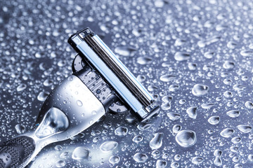 Razor close-up with water drops on a gray background.