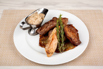 Fried meat in an assortment on a white plate with sauce.