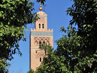 Fototapeta na wymiar Koutoubia Mosque and its beautiful Minaret in Marrakech its surrounded by beautiful trees and people resting and walking in its shadows