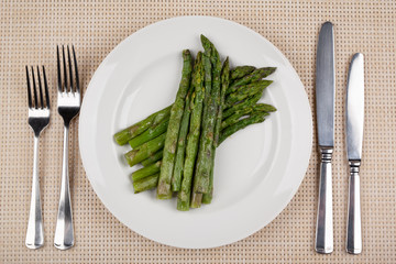 Green asparagus beans on a white round plate.