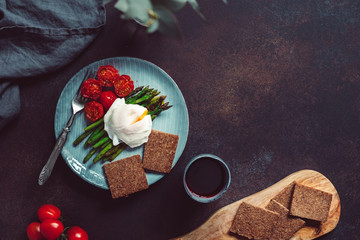 View from above on dinner or lunch for one, poached egg on grill asparagus and cherry tomatoes. Copy space.