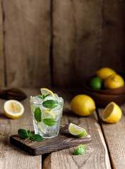 Mojito cocktail with lime, lemon and mint in a glass on a dark rustic background. Fresh summer cocktail. Lemon mojito