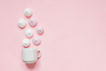 Top view of white and pink twisted meringues  on pink background. French dessert prepared from whipped with sugar and baked egg whites. Greeting card with copy space