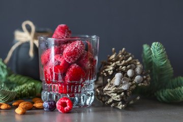 Frozen raspberry and blueberry berries fell out of a glass on a table. 