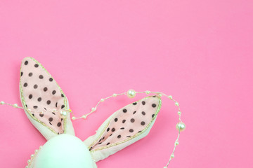 Easter egg decorated with pink ears of a hare with black peas.