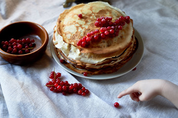 A stack of pancakes with red juicy currants.
