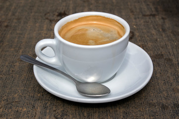 Cup of americano espresso coffee on white plate with spoon