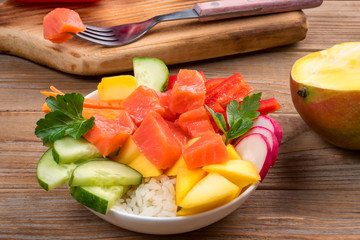 Poke salad from hawaii with fork on wooden background. Close up. Soft focus. To prepare it just take rice, salmon and any vegetables.7