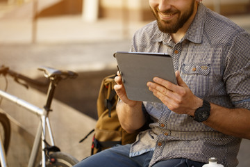 Handsome bearded male tourist using digital tablet at the city