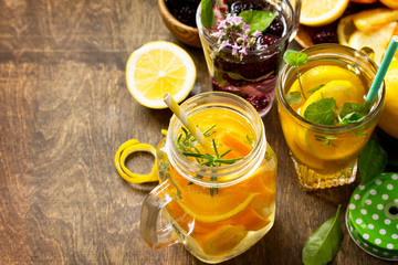 Refreshing summer berry Lemonade, lemon mint Tea and orange Lemonade with rosemary on wooden table in rustic style. Copy space.