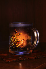 A transparent glass cup of invigorating tea at the edge of the table.