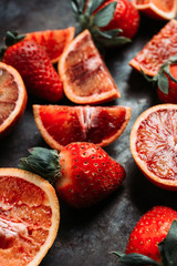 Fresh ripe strawberry and red oranges on the dark rustic background. Selective focus. Shallow depth of field.