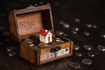 Miniature model house on treasure chest with coins. Concept of Investment management