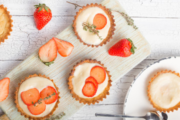   Save Download Preview Whole and slice of individual lemon curd tarts with strawberry  on a white rusty background. Flat lay and copy space.