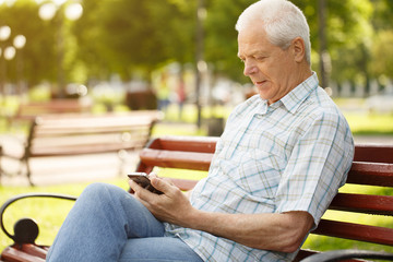 Senior man using smart phone at the park