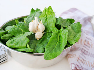 Fresh spinach leaves in metallic bowl over light background