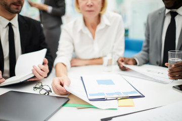 Cropped shot of unrecognizable businesswoman reading documents during meeting in office, copy space background