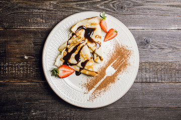 Russian thin pancakes (blini), with strawberry and chocolate sauce. Selective focus.