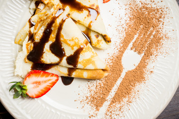 Russian thin pancakes (blini), with strawberry and chocolate sauce. Selective focus.