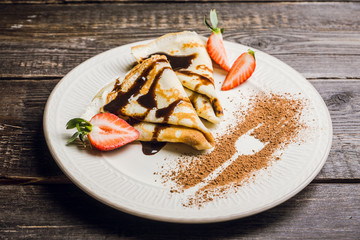 Russian thin pancakes (blini), with strawberry and chocolate sauce. Selective focus.
