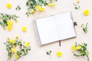 Yellow flowers, notebook on beige background, flat lay, top view