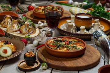View from above of georgian cuisine on brown wooden table. Traditional georgian cuisine and food - khinkali, kharcho, chahokhbili, phali, lobio and local sauces - tkemali, satsebeli, adzhika. Top view