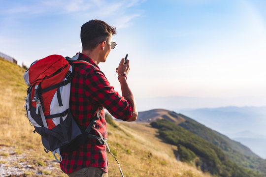 Italy, Monte Nerone, hiker on top of a mountain talking on a walkie talkie