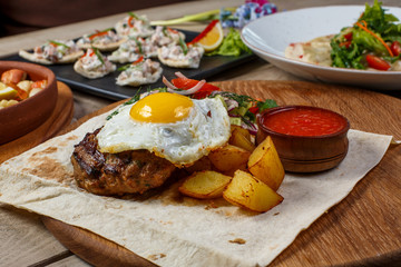 View from above of georgian cuisine on brown wooden table. Traditional georgian cuisine and food - khinkali, kharcho, chahokhbili, phali, lobio and local sauces - tkemali, satsebeli, adzhika. Top view