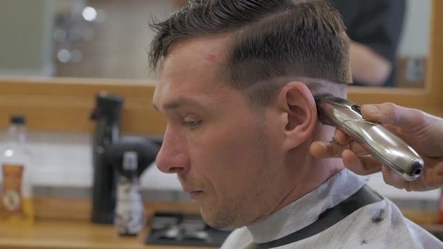 Close of man getting haircut at barber shop. Male hairstylist at work.	