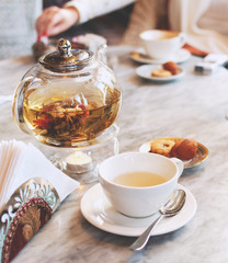 Transparent glass teapot with green tea on a table in a cafe, selective focus