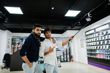 Two indians mans customer buyer at mobile phone making selfie by monopod stick. South asian peoples and technologies concept. Cellphone shop.