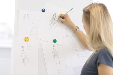 Female fashion designer drawing fashion sketches at her studio