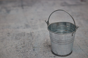Empty small metal bucket isolated on a concrete background. copy space. horizontal view.