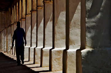 Fototapeta premium Columns and Man Walking Away, Mission San Miguel, California 