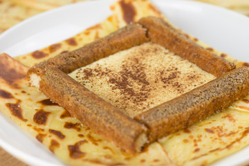 Delicious tiramisu crepe filled with mascarpone, coffee and chocolate powder. French crepe with italian tiramisu