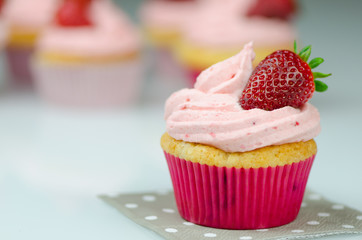 Delicious pink strawberry cupcake with a strawberry. Cupcakes and pink icing with a strawberries on...