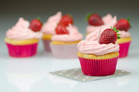 Delicious pink strawberry cupcake with a strawberry. Cupcakes and pink icing with a strawberries on top