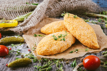Homemade breaded uncooked cutlets on a wooden table in a rustic style. Healthy food.