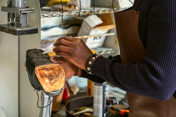 Shoemaker puts the glue on the sole of a shoe